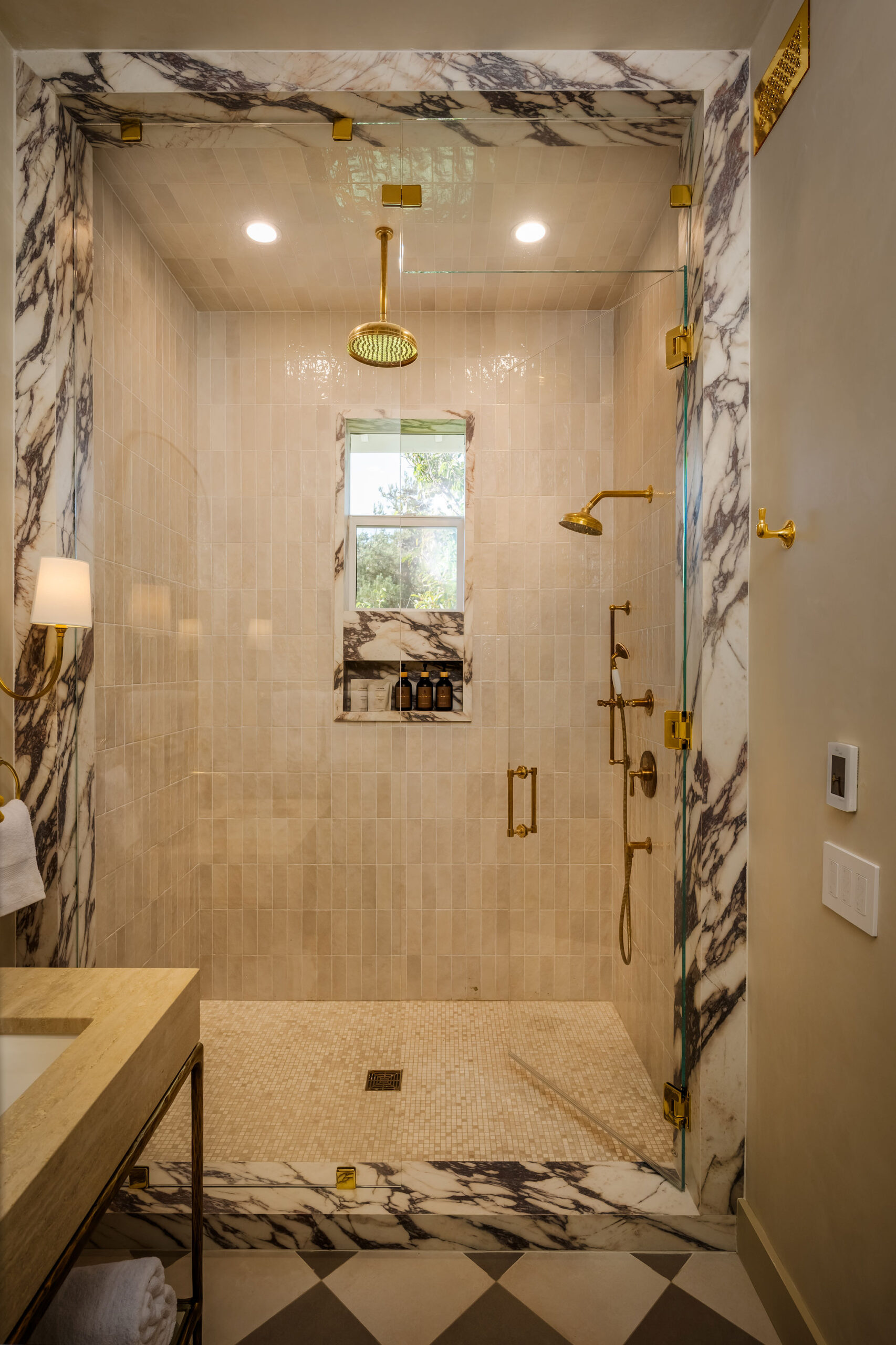 A marble walk-in shower with brass fixtures at The Polo House